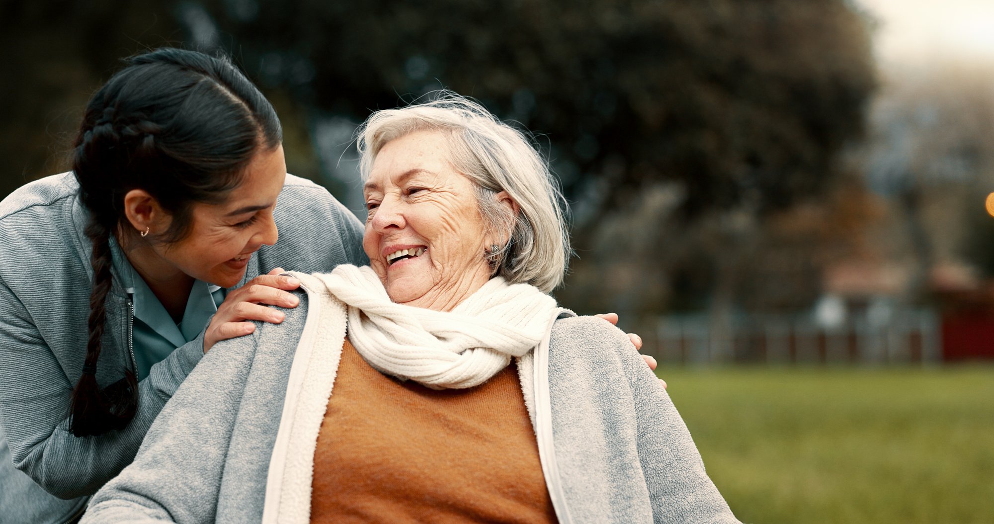 Older and younger women looking at each other and smiling in a park Older and younger women looking at each other and smiling in a park